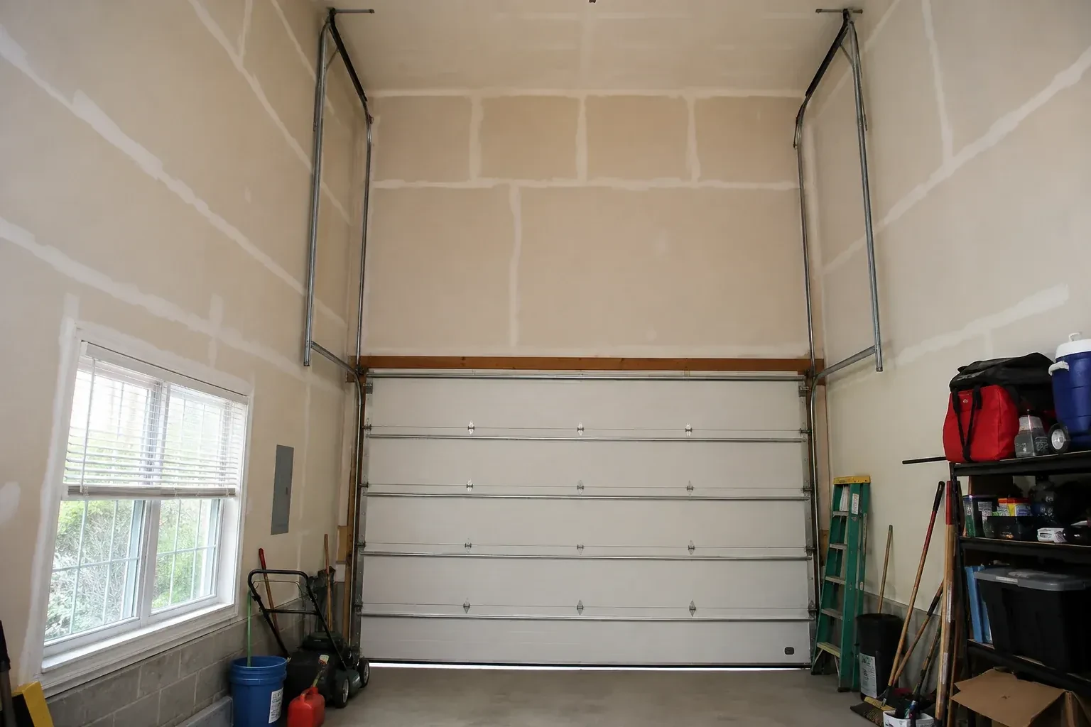 Tall garage interior with a sectional door and tracks extending into overhead space. — High-Lift Garage Door Conversion, Toronto