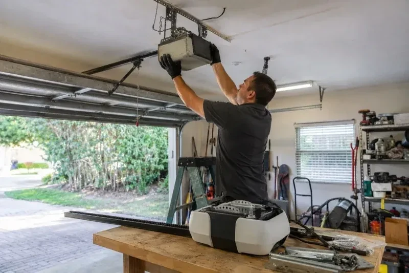 Person holding an overhead garage-door opener beside another opener and hardware on a workbench — Garage Door Opener Replacement, Toronto